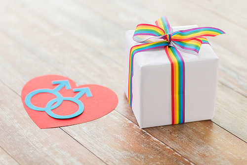 homosexual and lgbt concept - close up of gift box with gay pride awareness ribbon and male gender symbol on heart on wooden boards