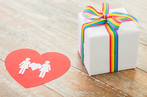 homosexual and lgbt concept - close up of gift box with gay pride awareness ribbon and female couple pictogram on red paper heart on wooden boards