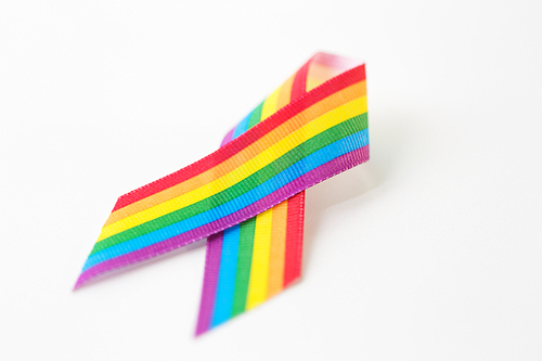 homosexual and lgbt concept - close up of gay pride awareness ribbon on white background
