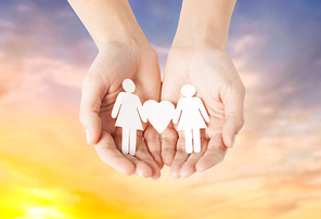 lgbt and gay concept - hands holding paper female couple pictogram with heart over evening sky background
