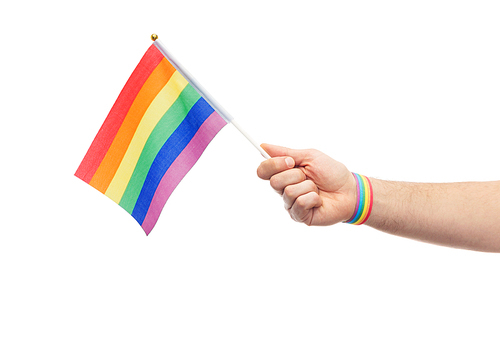 lgbt, same-sex relationships and homosexual concept - close up of male hand wearing gay pride awareness wristband holding rainbow flag