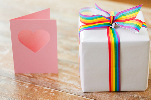 homosexual and lgbt concept - gift box with gay pride awareness ribbon and greeting card on wooden table