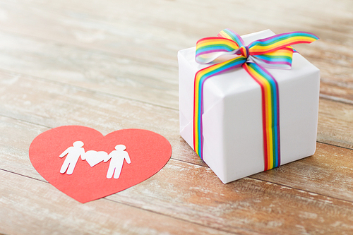homosexual and lgbt concept - close up of gift box with gay pride awareness ribbon and male couple pictogram on red paper heart on wooden boards