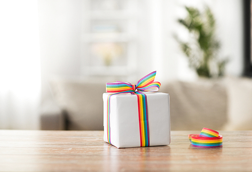 homosexual and lgbt concept - gift box with gay pride awareness ribbon on wooden table at home