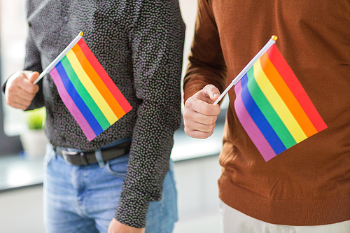 gay pride, lgbt and homosexual concept - close up of male couple with rainbow flags