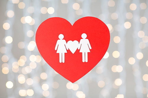 gay pride, homosexual, valentines day and lgbt concept - female couple white paper pictogram on red heart over festive lights background