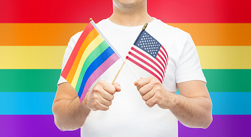 lgbt, same-sex relationships and homosexual concept - close up of man holding gay pride rainbow and american flag
