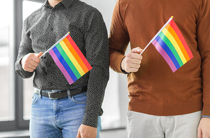 gay pride, lgbt and homosexual concept - close up of male couple with rainbow flags