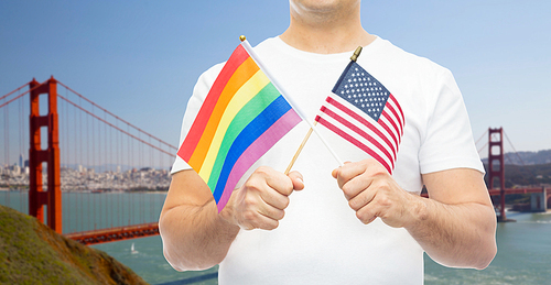 lgbt, same-sex relationships and homosexual concept - close up of man holding gay pride rainbow and american flag over golden gate bridge in san francisco bay background