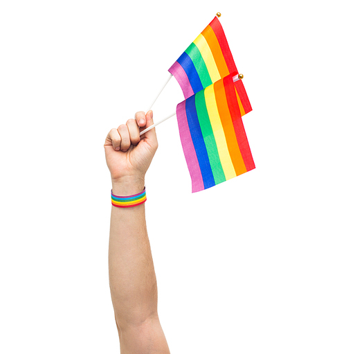 lgbt, same-sex relationships and homosexual concept - close up of male hand wearing gay pride awareness wristband holding rainbow flags