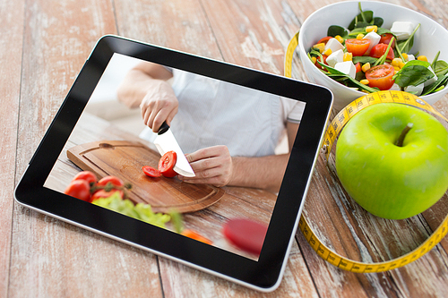 healthy eating, diet and technology concept - close up of tutorial cooking video on tablet computer screen, green apple, measuring tape and salad