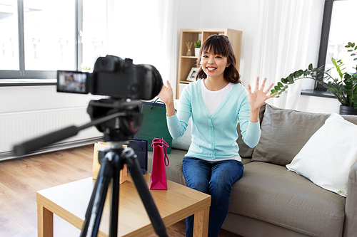 blogging, technology, videoblog and people concept - happy smiling asian woman or . with shopping bags recording video blog by camera at home
