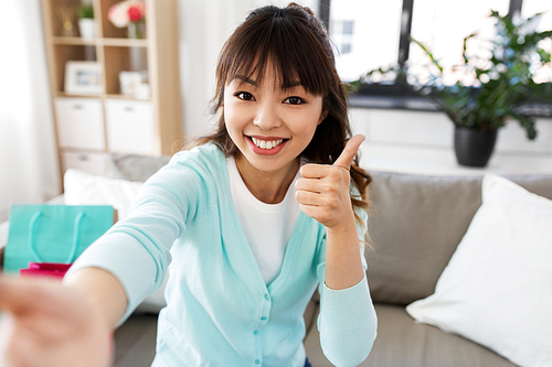 blogging, videoblog and technology concept - asian woman or . recording video blog or taking selfie and showing thumbs up at home