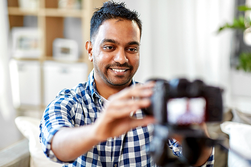 blogging, videoblog and people concept - smiling indian male video . adjusting camera at home