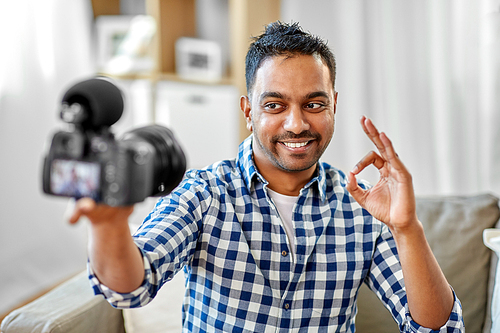 blogging, videoblog and people concept - smiling indian male video . with camera videoblogging making ok gesture at home
