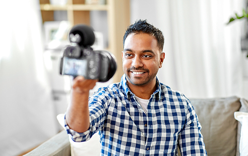 blogging, videoblog and people concept - smiling indian male video . with camera videoblogging at home