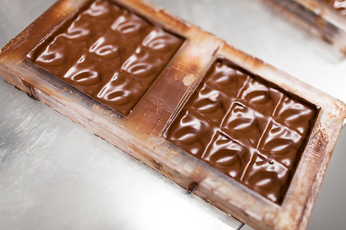 production and cooking concept - close up of chocolate cream in candy mold at confectionery shop