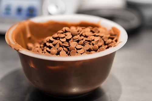 culinary and cooking concept - close up of chocolate buttons in bowl at confectionery shop
