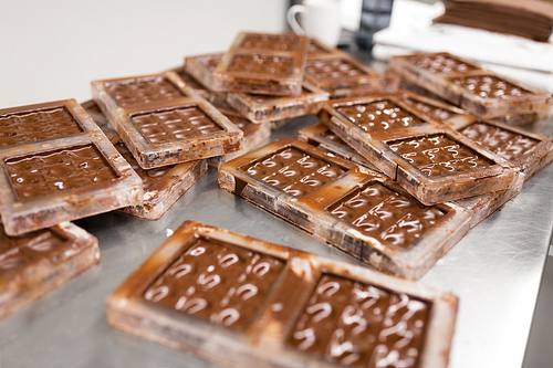 production and cooking concept - close up of chocolate cream in candy molds at confectionery shop
