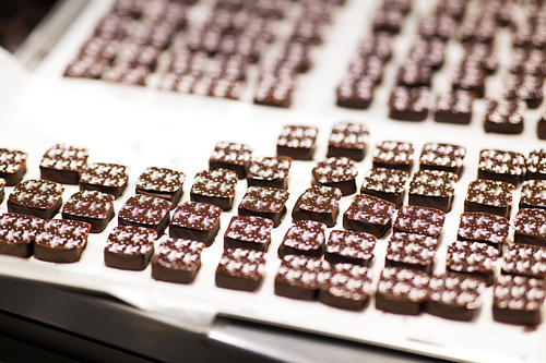 sweets production and industry concept - chocolate candies at confectionery shop