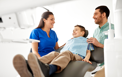 medicine, dentistry and healthcare concept - happy father and son visiting dentist at dental clinic