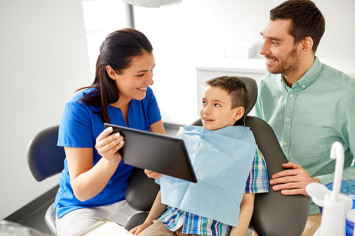medicine, dentistry and healthcare concept - dentist showing tablet pc computer to kid patient and his father at dental clinic
