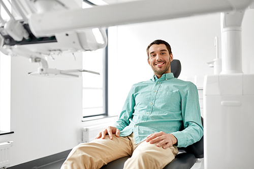 medicine, dentistry and healthcare concept - happy smiling male patient on chair at dental clinic
