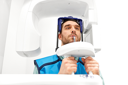 medicine, dentistry and healthcare concept - male patient having panoramic x-ray scanning procedure at dental clinic