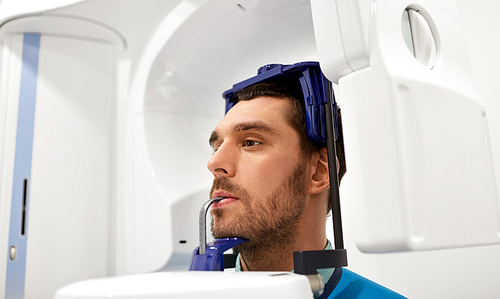 medicine, dentistry and healthcare concept - male patient having panoramic x-ray scanning procedure at dental clinic