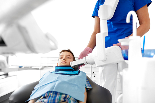 medicine, dentistry and healthcare concept - female dentist with x-ray machine scanning kid patient teeth at dental clinic