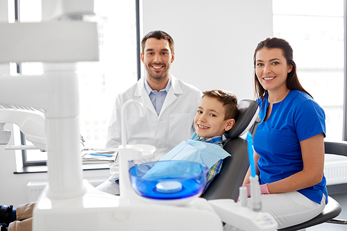 medicine, dentistry and healthcare concept - happy dentist, assistant and kid patient at dental clinic