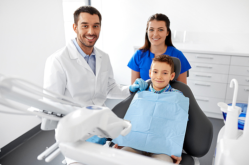 medicine, dentistry and healthcare concept - happy dentist, assistant and kid patient at dental clinic