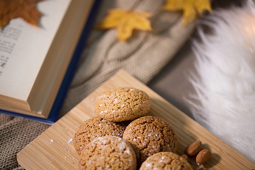 hygge, food and baking concept - oatmeal cookies on wooden board at home