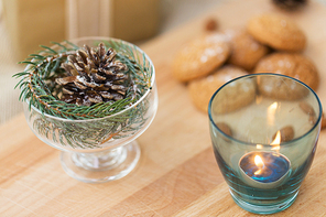 christmas concept - decoration of fir twig with pinecone in ice cream glass or dessert bowl and candle in holder