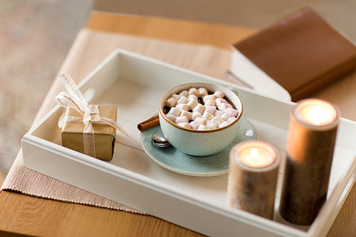 holidays and still life concept - hot chocolate with marshmallow, christmas gift and candles on table