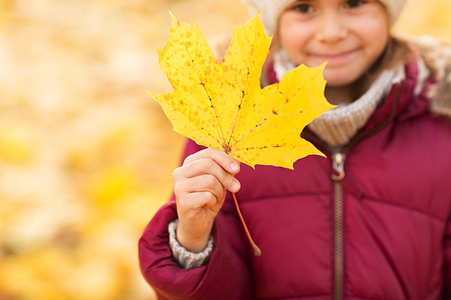 childhood, season and people concept - close up of little girl with maple leaf in autumn
