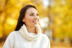 season and people concept - portrait of happy young woman smiling in autumn park