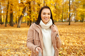 season, technology and people concept - beautiful young happy woman taking picture by selfie stick at autumn park