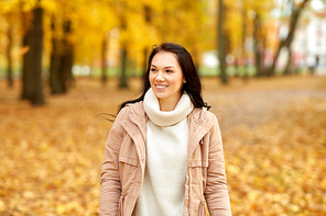 season, emotions, facial expression and people concept - happy young woman smiling in autumn park