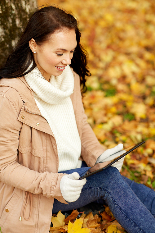 season, technology and people concept - beautiful happy young woman with tablet pc computer at autumn park