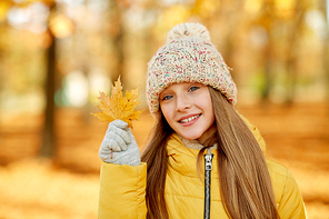 childhood, season and people concept - portrait of happy girl with maple leaf at autumn park