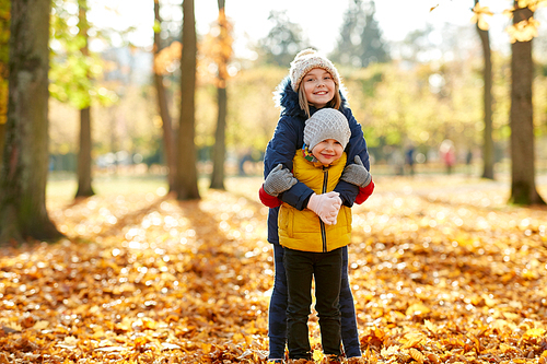 childhood, season and family concept - happy children hugging at autumn park