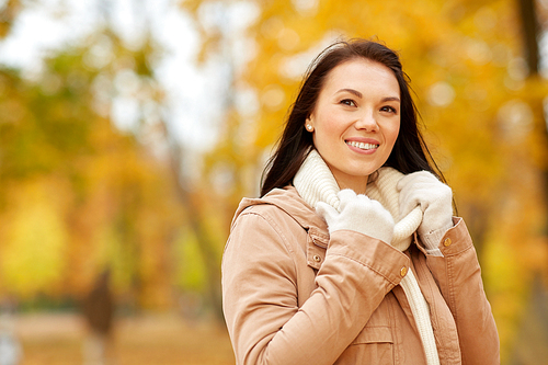 season, fashion and people concept - happy young woman smiling in autumn park