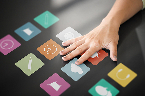 technology and people concept - hand using interactive panel with app icons on it