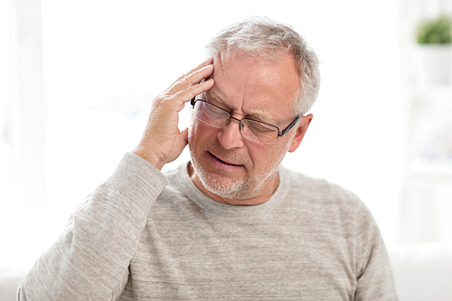 health care, stress, old age and people concept - senior man suffering from headache at home