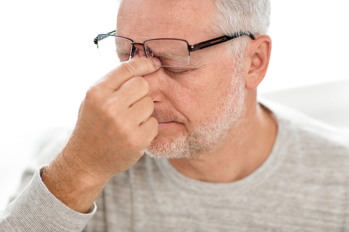 stress, old age and people concept - close up of senior man in glasses having headache and massaging nose bridge