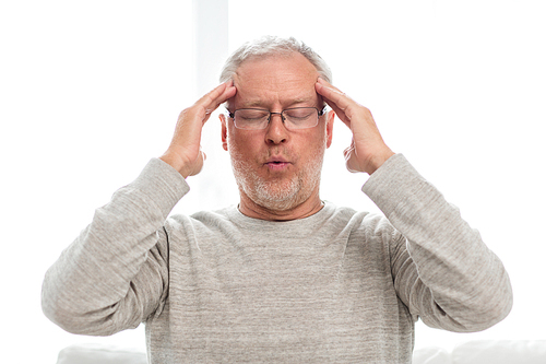 health care, stress, old age and people concept - senior man suffering from headache at home