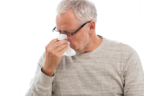 healthcare, flu, hygiene and people concept - sick senior man with paper wipe blowing his nose at home