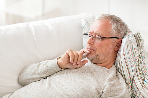 old age, problem and people concept - senior man  lying on sofa and thinking at home