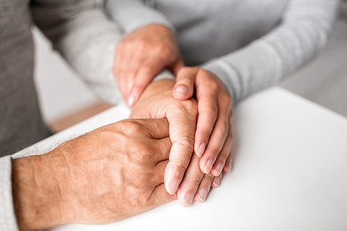 old age, family, care and support concept - close up of young woman holding senior man hands